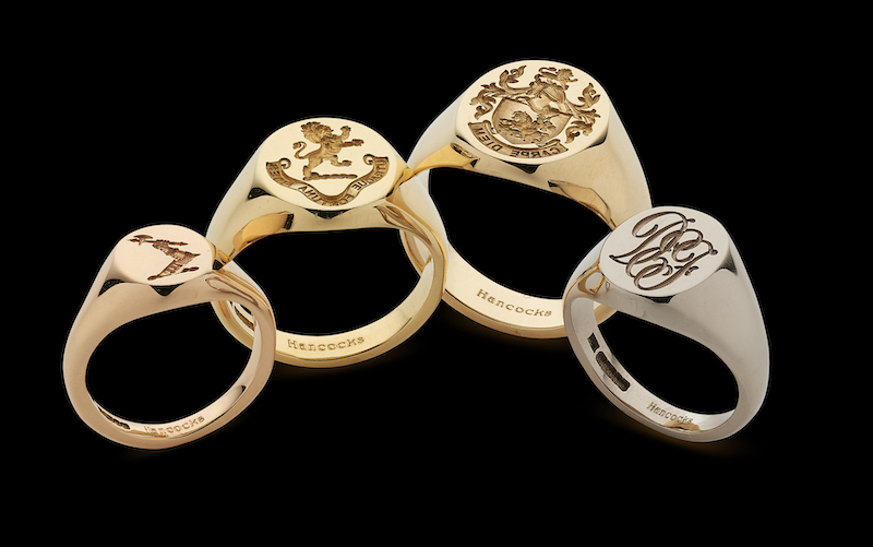 Four signet rings in various metal colours and sizes. They are engraved with different symbols